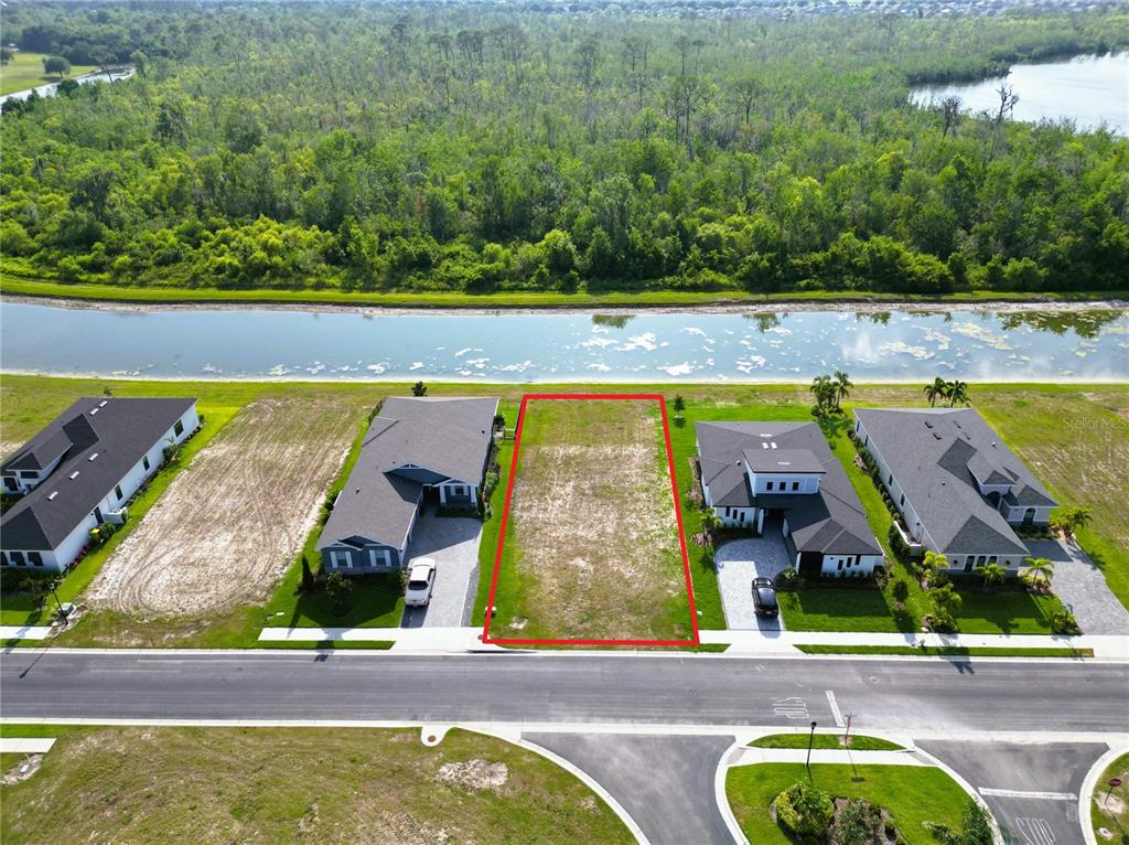 An aerial view shows a vacant rectangular residential lot outlined in red between two houses — 465 ADAMS VIEW LANE, AUBURNDALE, FL