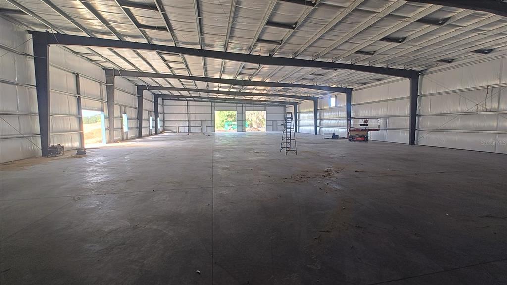 A construction site shows a metal warehouse building with two large bays and a worker — 12142 SE COUNTY 484 HIGHWAY, BELLEVIEW, FL