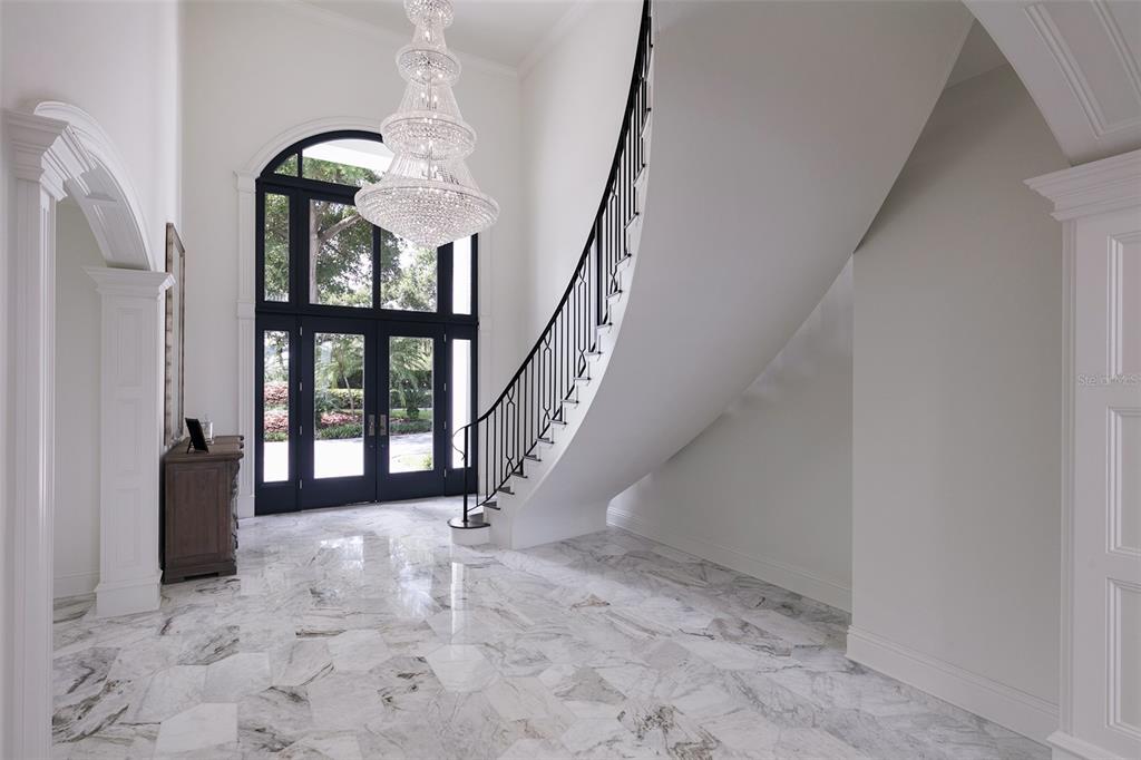 A grand foyer features marble flooring, a curved staircase, and a large crystal chandelier — 6462 DEACON CIR, WINDERMERE, FL