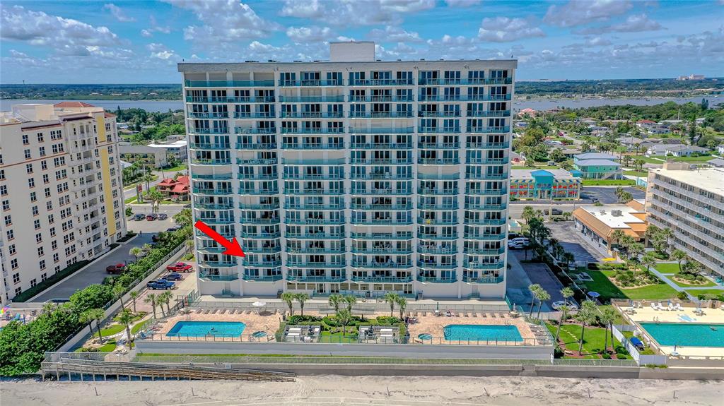 An exterior view of a tall beachfront condominium building with two swimming pools below — 2055 S ATLANTIC AVENUE UNIT 307, DAYTONA BEACH SHORES, FL
