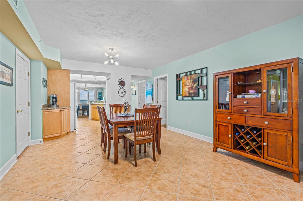 A dining room with tile floors, a wooden table with chairs, and a large hutch — 2055 S ATLANTIC AVENUE UNIT 307, DAYTONA BEACH SHORES, FL