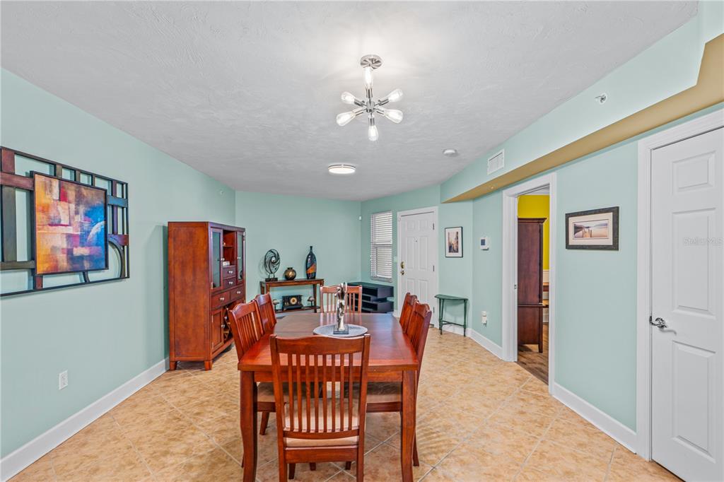 A dining room with light blue walls, tile flooring, a wooden table, and a chandelier — 2055 S ATLANTIC AVENUE UNIT 307, DAYTONA BEACH SHORES, FL