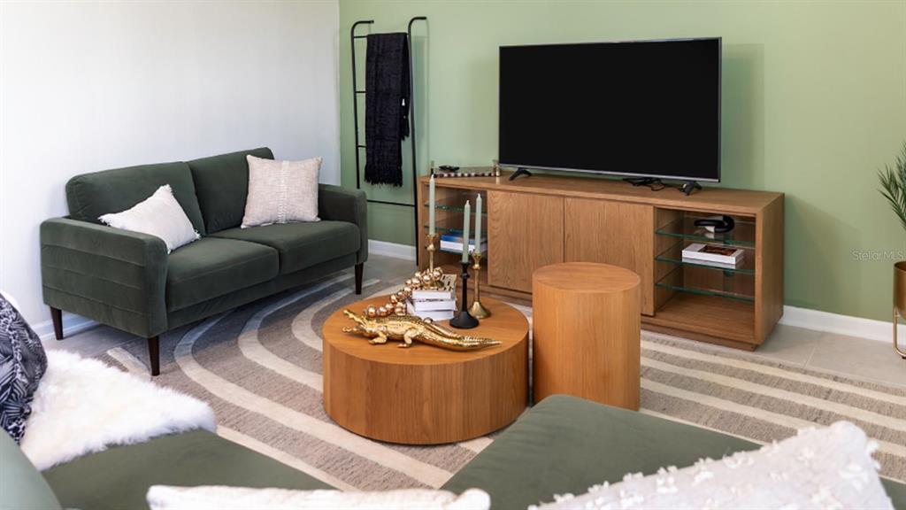 A living room features a green sofa, a round wooden coffee table, and a television console — 6081 ZEN WAY, CLERMONT, FL