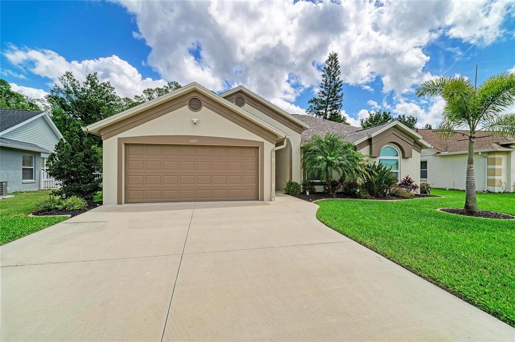 A single-story suburban house with a tan stucco exterior, a two-car garage, and a driveway — 1007 50TH STREET E, BRADENTON, FL
