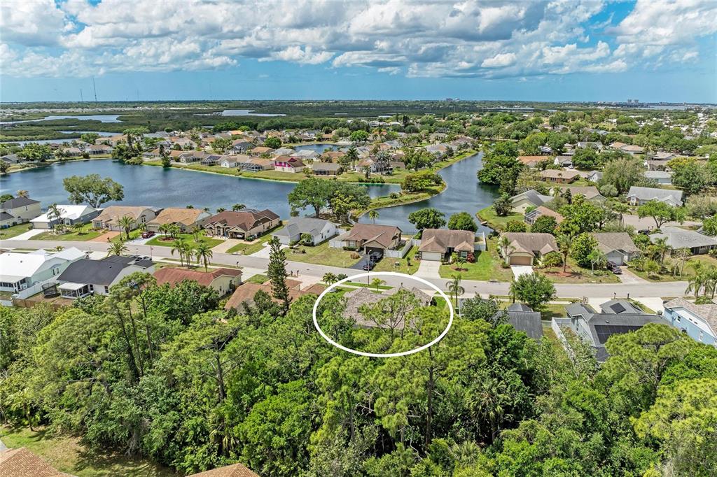 An aerial view shows a residential house surrounded by trees and a nearby lake — 1007 50TH STREET E, BRADENTON, FL