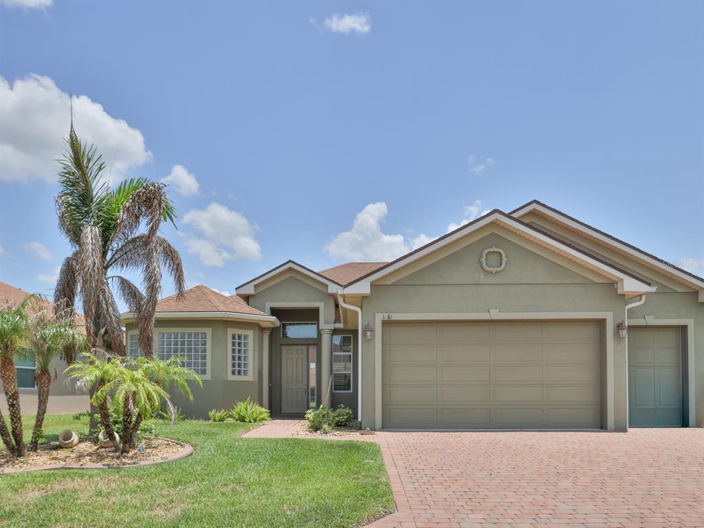 A single-story house with a brick driveway, a two-car garage, and a palm tree — 1061 SAWGRASS DRIVE, WINTER HAVEN, FL