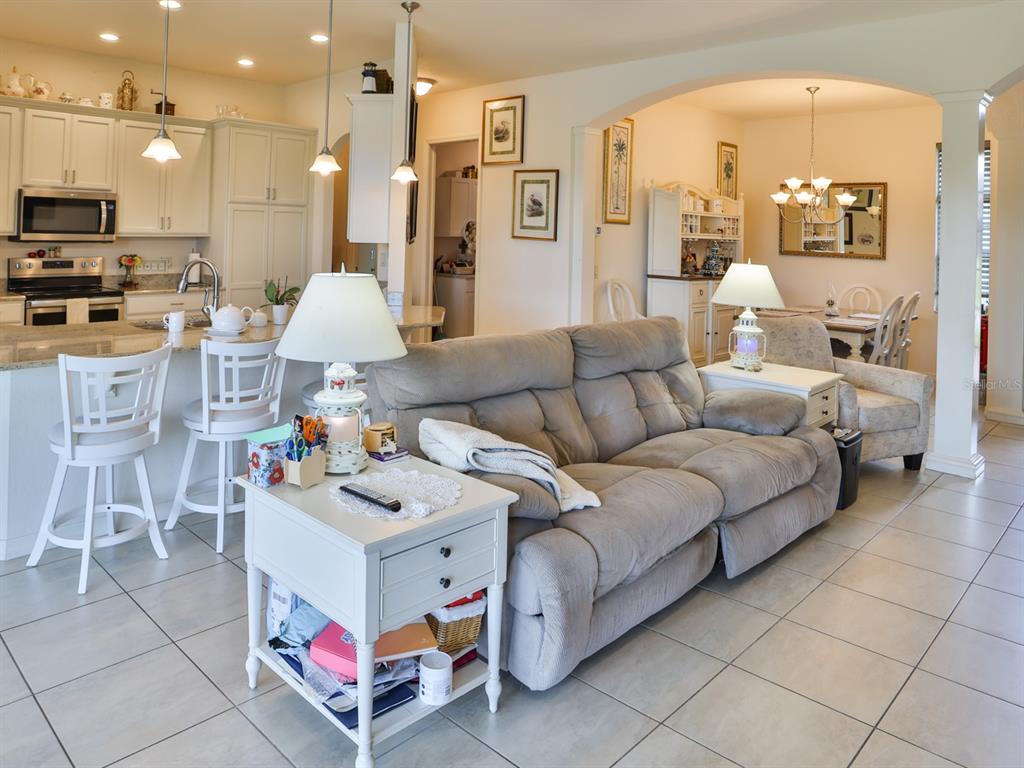 An open-concept living room with a grey sofa, kitchen island, and dining area — 1061 SAWGRASS DRIVE, WINTER HAVEN, FL