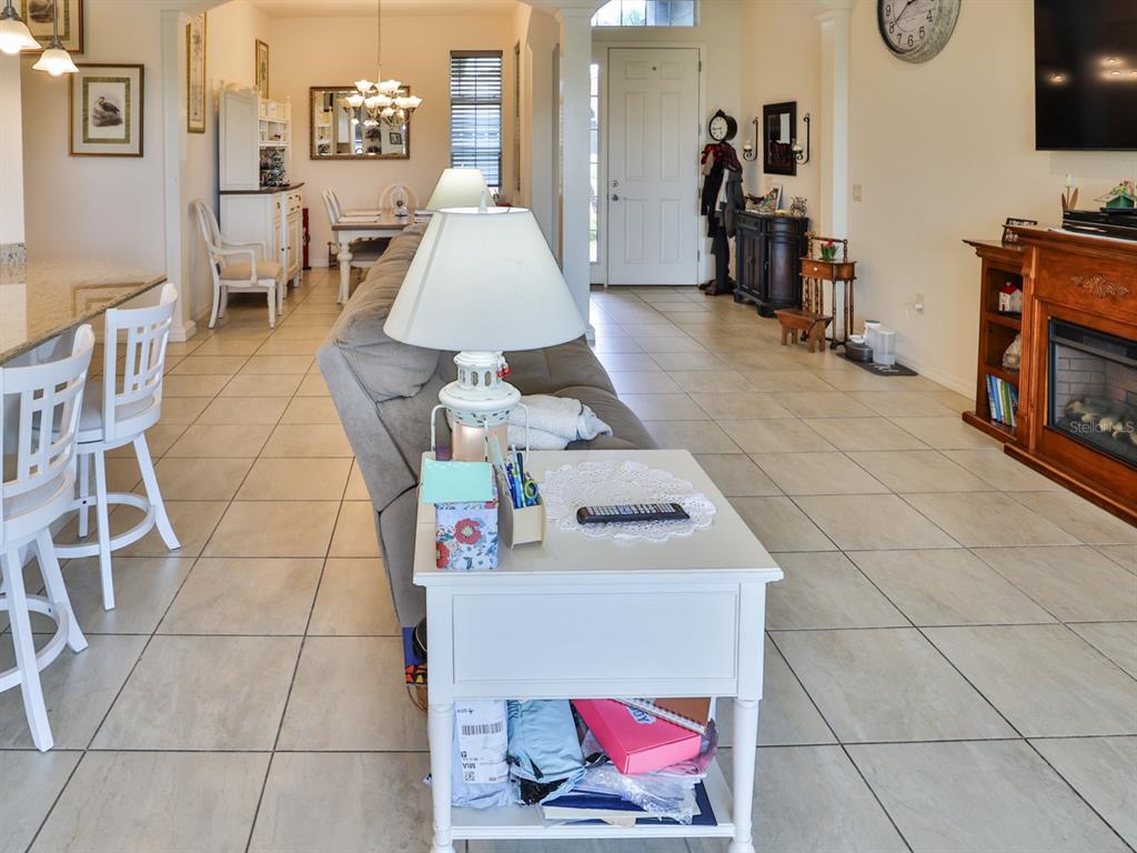 A living room with tile floors, a gray sofa, a white end table, and a fireplace — 1061 SAWGRASS DRIVE, WINTER HAVEN, FL