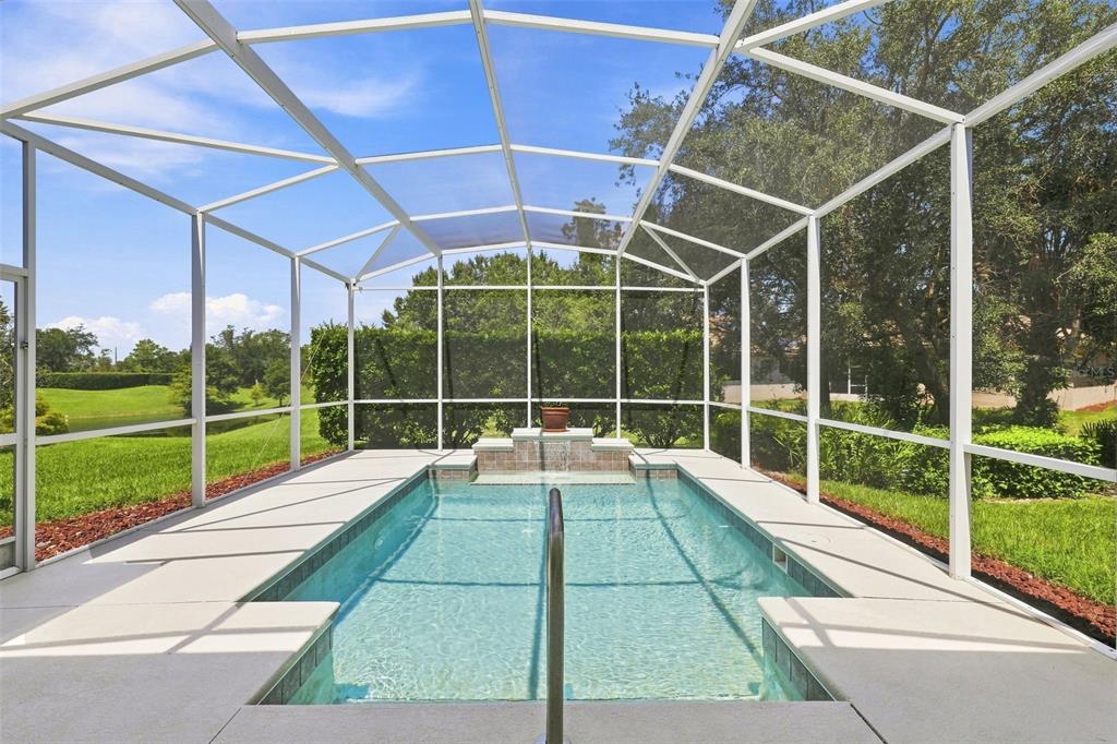 A rectangular swimming pool with a water feature is enclosed by a white screen cage — 437 SOTHEBY WAY, DEBARY, FL