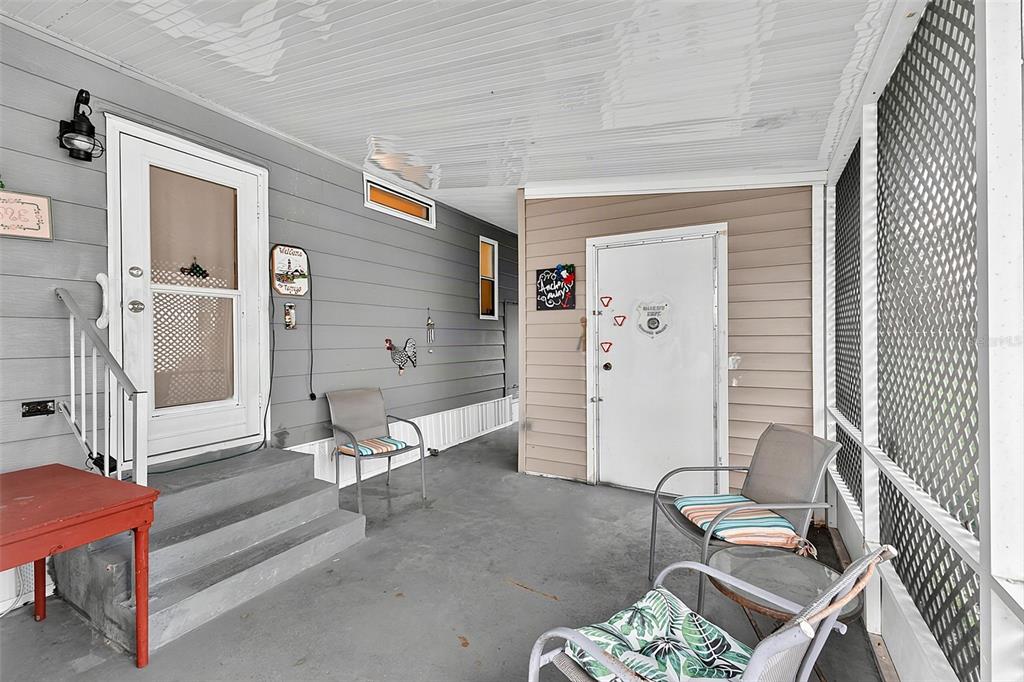 A covered porch features gray siding, a concrete floor, two entry doors, and patio furniture — 417 VILLA NUEVA CIRCLE, NORTH PORT, FL