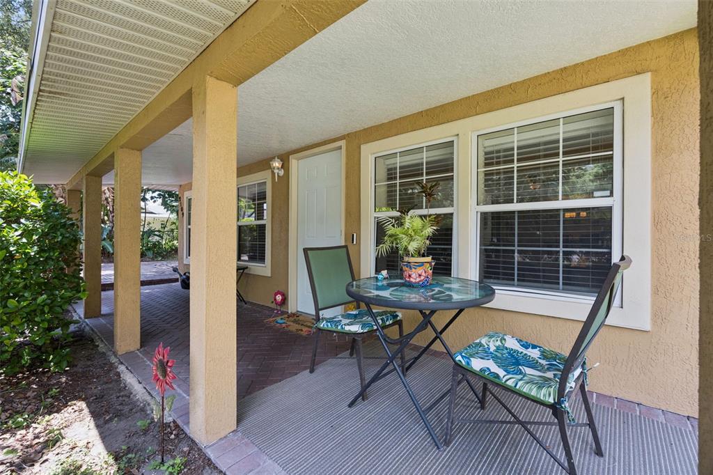 A covered brick patio features a small glass-topped table with two chairs and large windows — 2109 E GRANT AVENUE, ORLANDO, FL