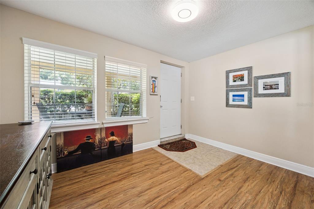 A room with wood-look flooring, a tiled entryway, two windows, and wall-mounted artwork — 2109 E GRANT AVENUE, ORLANDO, FL