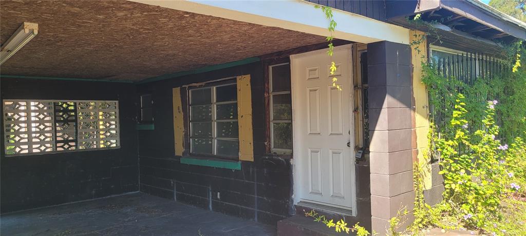 An exterior view of a house with a covered porch, dark walls, and a white door — 5451 LILY ROAD, LAKELAND, FL