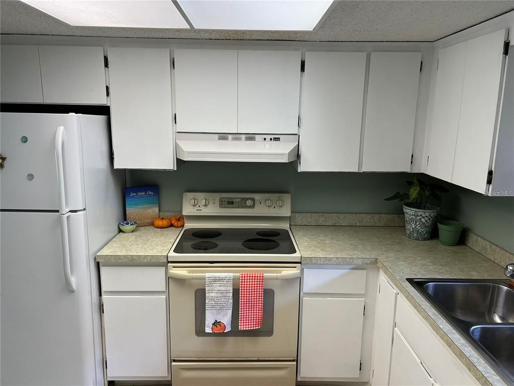 A kitchen features white cabinets, a white stove, and light-colored laminate countertops — 1100 E BAY DRIVE UNIT 35, LARGO, FL