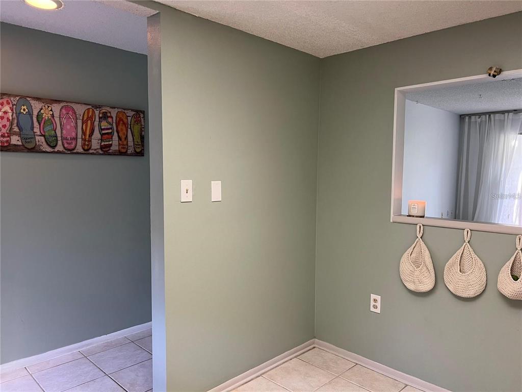 A sage green room features a pass-through window, tiled flooring, and wall-mounted decor — 1100 E BAY DRIVE UNIT 35, LARGO, FL