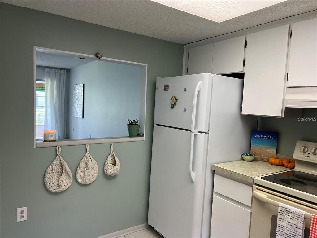 A kitchen features a pass-through window, white appliances, and three hanging woven baskets on the wall — 1100 E BAY DRIVE UNIT 35, LARGO, FL