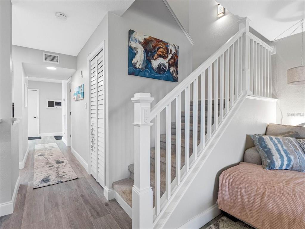 A staircase with white railings and carpeted steps sits beside a hallway with wood flooring — 4306 SUNRAY COURT, TAMPA, FL