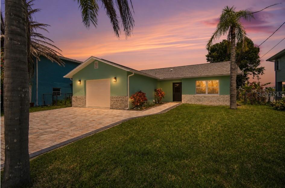 A green single-story house with a stone-accented facade, a paved driveway, and a palm tree — 4482 KINGSTON DRIVE, HERNANDO BEACH, FL