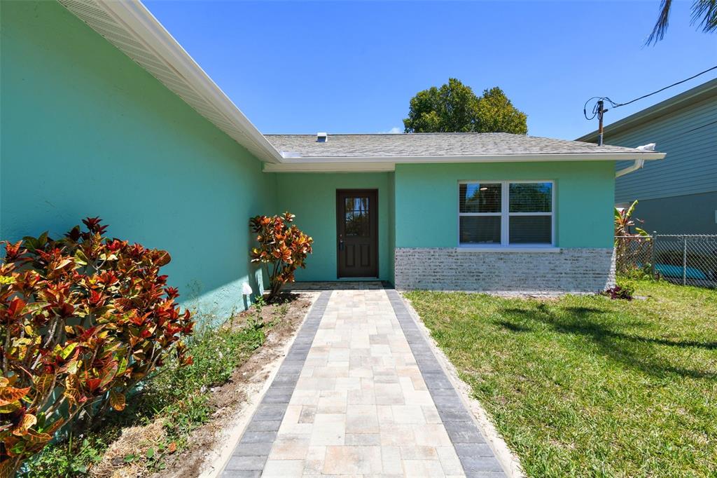 A teal house exterior features a stone-accented wall, a paved walkway, and a front door — 4482 KINGSTON DRIVE, HERNANDO BEACH, FL