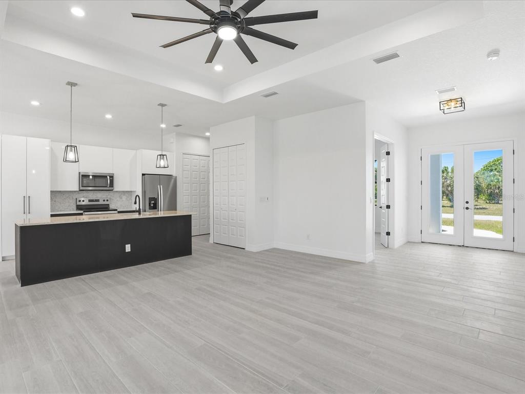 A modern open-concept kitchen and living area with white cabinetry, a black island, and tile flooring — 72 TEE VIEW ROAD, ROTONDA WEST, FL