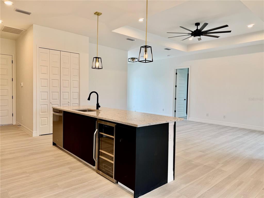 A modern kitchen features a white island, dark cabinetry, stainless steel appliances, and pendant lighting — 72 TEE VIEW ROAD, ROTONDA WEST, FL