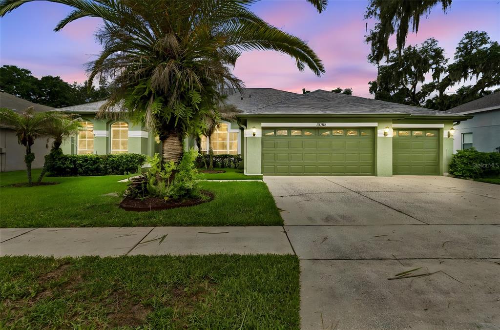 An open-concept dining and living area features hardwood floors, a crystal chandelier, and sliding doors — 2005 WEXFORD GREEN DRIVE, VALRICO, FL