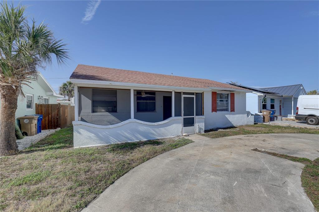 A single-story house with a screened front porch, a concrete driveway, and a palm tree — 440 S BAYSHORE DRIVE, MADEIRA BEACH, FL
