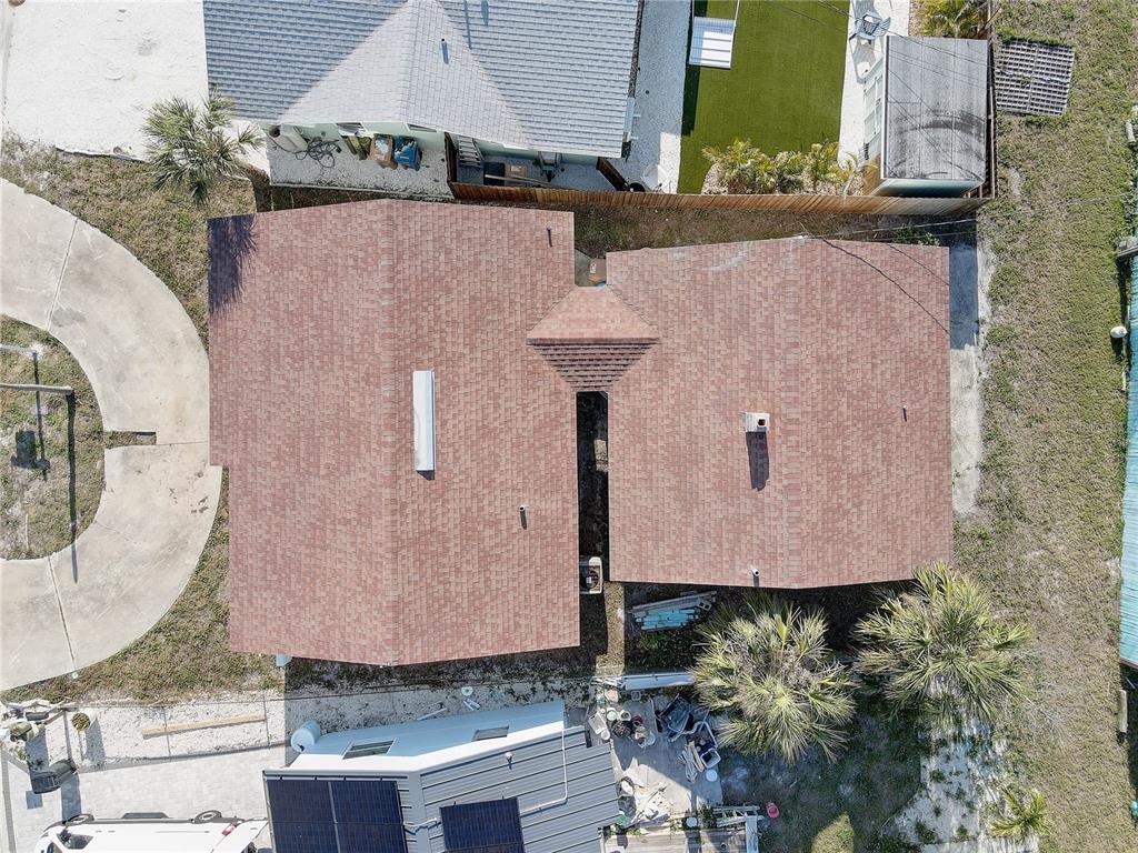 An aerial view shows the brown shingled roof of a house with a central skylight — 440 S BAYSHORE DRIVE, MADEIRA BEACH, FL