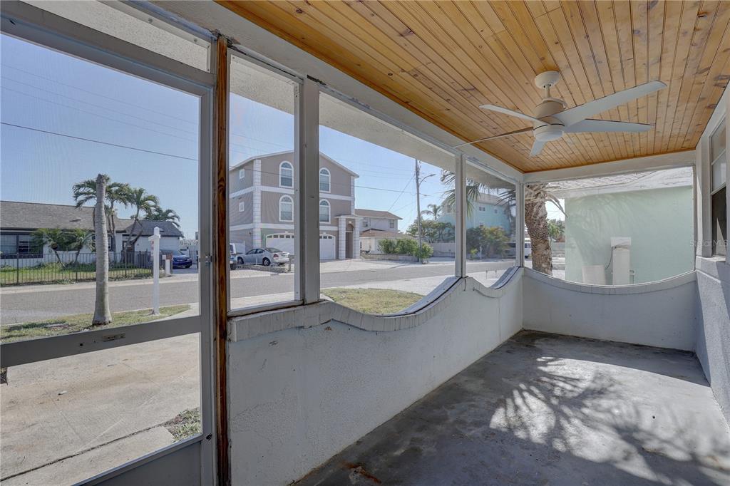 A screened-in porch features a wood-paneled ceiling, a ceiling fan, and a concrete floor — 440 S BAYSHORE DRIVE, MADEIRA BEACH, FL