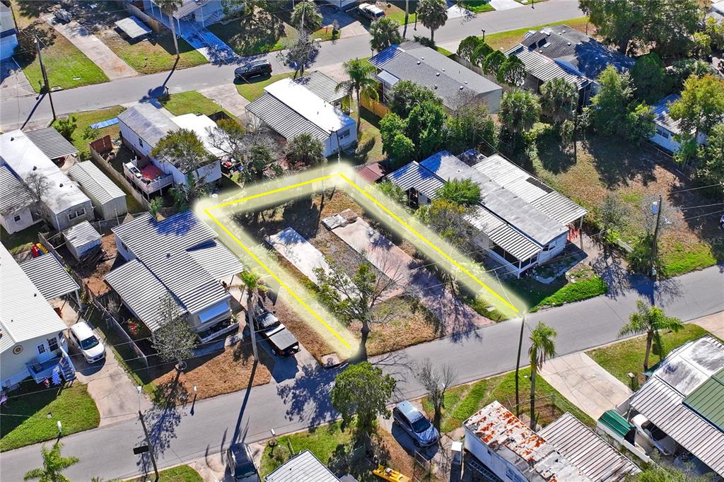 A vacant lot features a concrete slab foundation surrounded by grass, trees, and a fence — 736 DRIFTWOOD LANE, TARPON SPRINGS, FL