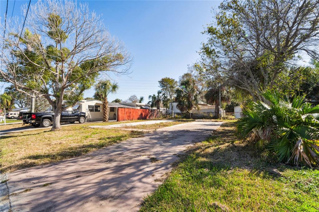 An aerial view shows a vacant rectangular lot highlighted in yellow between two residential buildings — 736 DRIFTWOOD LANE, TARPON SPRINGS, FL