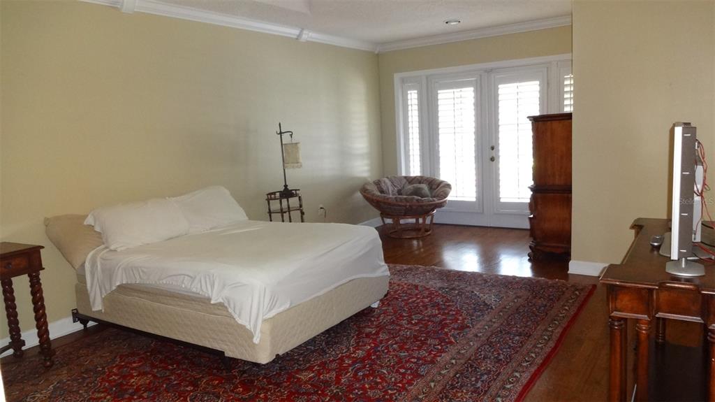 A bedroom with a bed, a red patterned rug, a chair, and a television stand — 1144 DELANEY AVENUE UNIT 1144, ORLANDO, FL