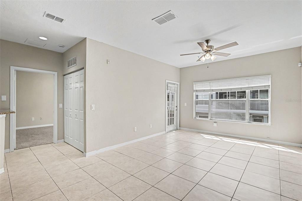 An empty room with beige tile flooring, a ceiling fan, and a glass-paneled door — 2460 GRAND CENTRAL PARKWAY UNIT 9, ORLANDO, FL