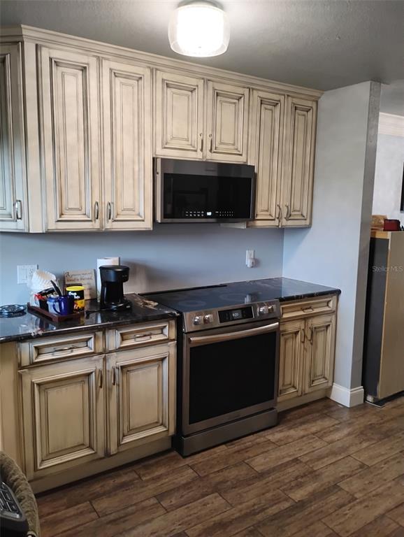 A kitchen features cream-colored cabinets with dark glazing, stainless steel appliances, and dark countertops — 2101 N ATLANTIC AVENUE UNIT 18, DAYTONA BEACH, FL