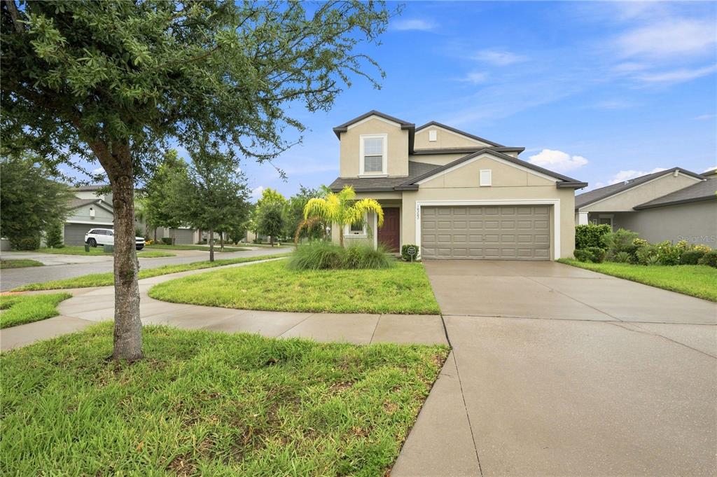 A two-story suburban house with a tan stucco exterior, a two-car garage, and a driveway — 10202 HAPPY HEART AVENUE, RIVERVIEW, FL
