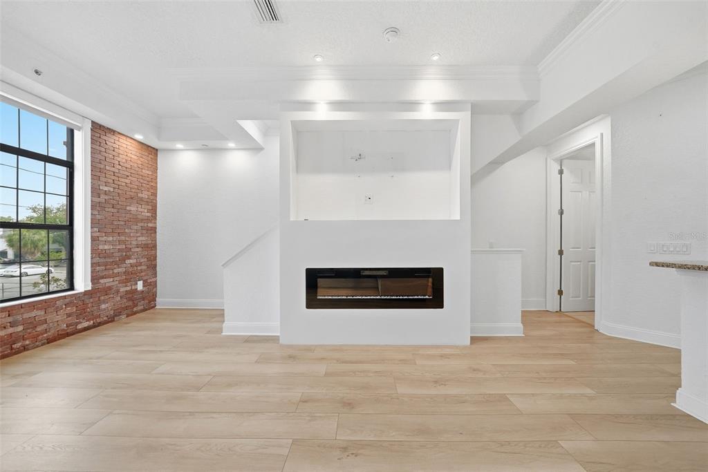 A living room features light wood flooring, a brick accent wall, and a central fireplace unit — 2236 SOHO BAY COURT, TAMPA, FL
