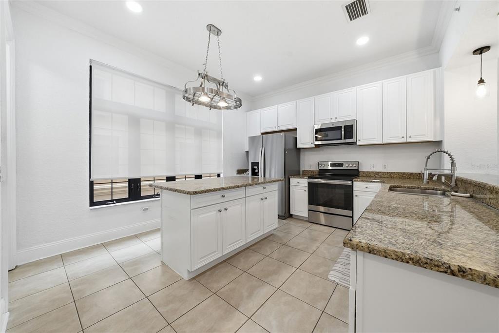 A kitchen with white cabinets, granite countertops, stainless steel appliances, and a central island — 2236 SOHO BAY COURT, TAMPA, FL
