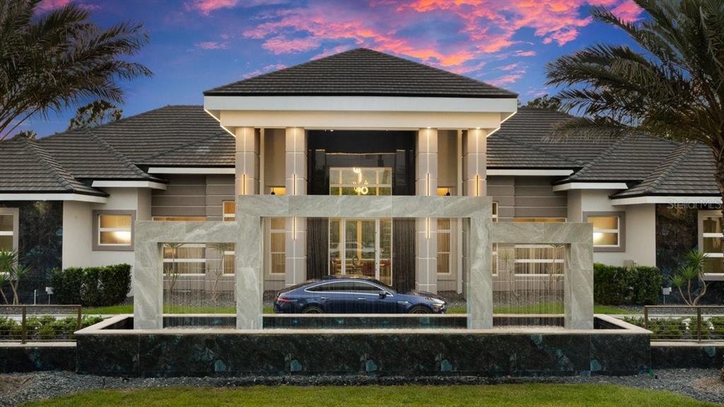 A modern house exterior features a large stone water fountain in front of the entrance — 420 WINGSPAN DRIVE, ORMOND BEACH, FL