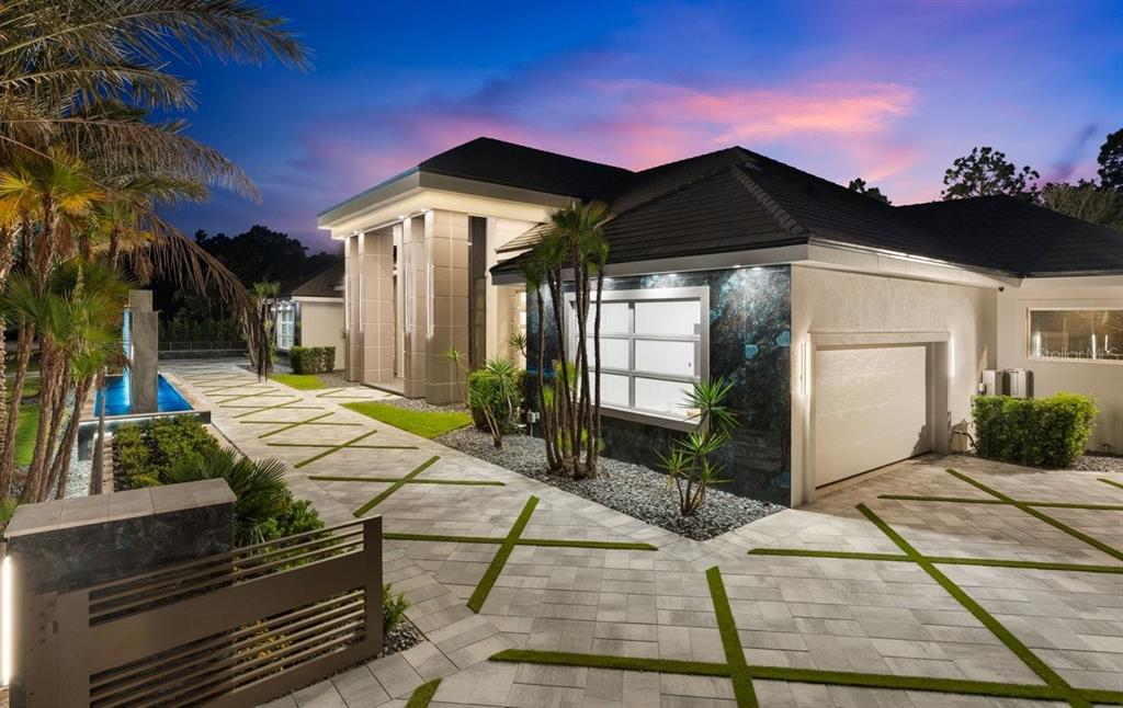 A modern house exterior features a paved driveway with grass strips and a stone facade — 420 WINGSPAN DRIVE, ORMOND BEACH, FL