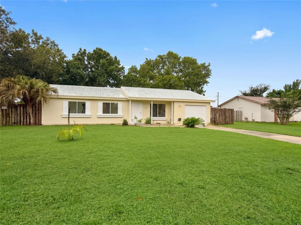 A single-story house with a white metal roof, light-colored siding, and a concrete driveway — 731 SW 24TH STREET, VERO BEACH, FL
