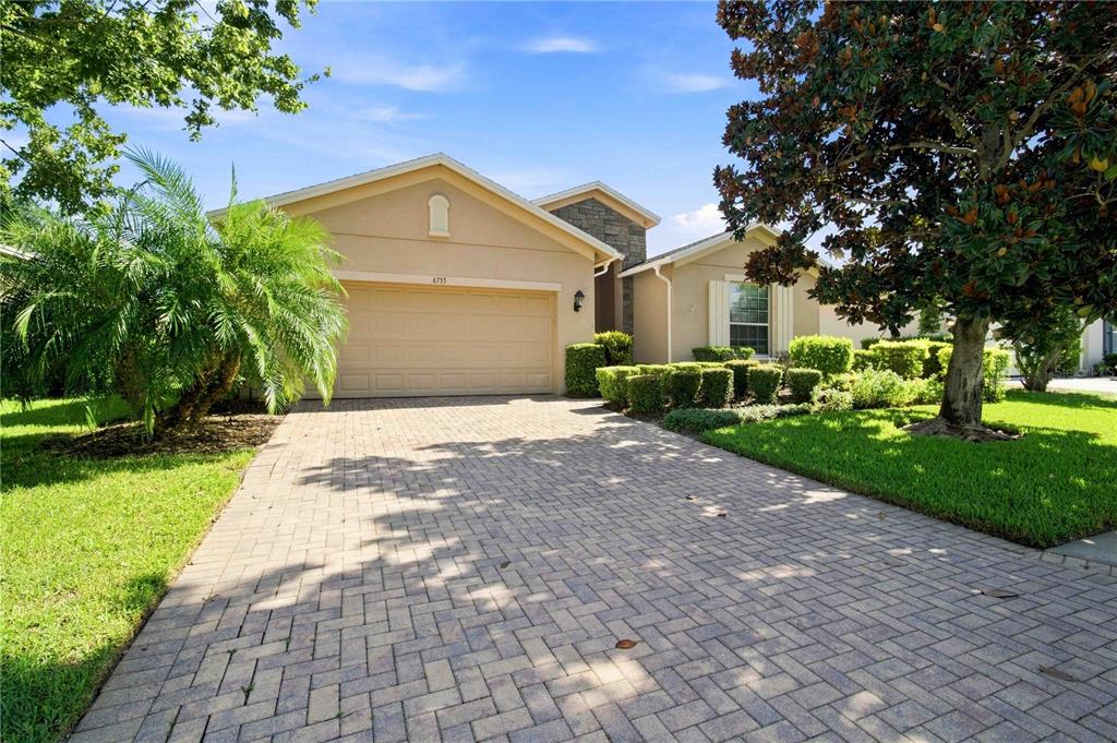 A single-story house with a beige stucco exterior, a paved driveway, and manicured landscaping — 6733 45TH TERRACE E, BRADENTON, FL