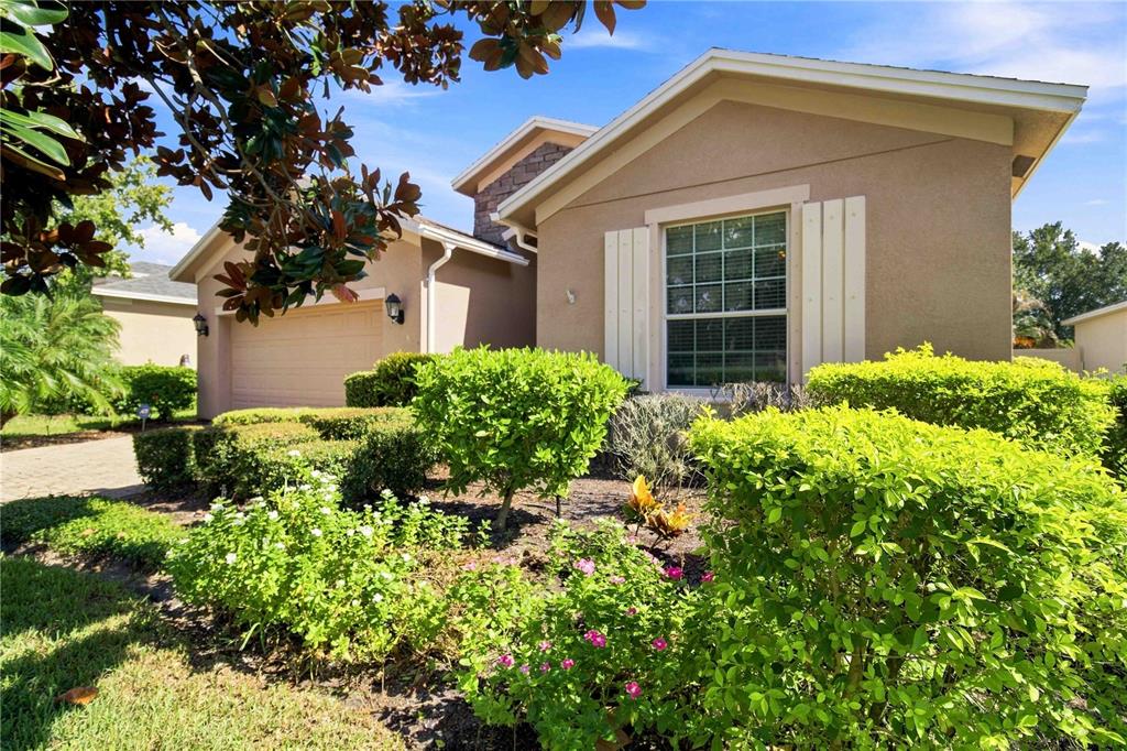 A tan single-story house with a two-car garage and landscaped front yard — 6733 45TH TERRACE E, BRADENTON, FL