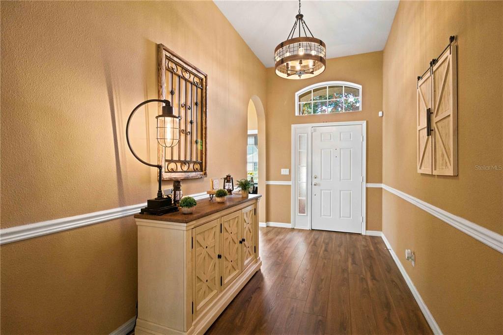 A foyer features wood-look flooring, tan walls with chair rail molding, and a wooden console table — 6733 45TH TERRACE E, BRADENTON, FL