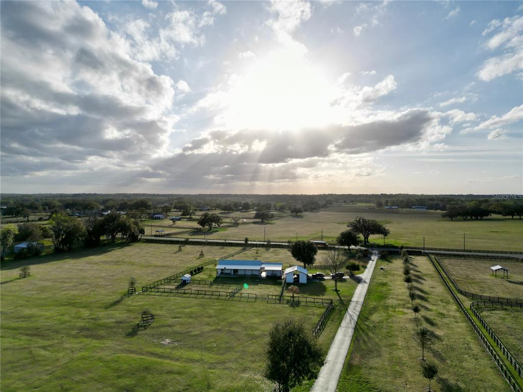 An aerial view shows a rural property with a house, outbuildings, and fenced pastures — 12895 NW GAINESVILLE ROAD, REDDICK, FL