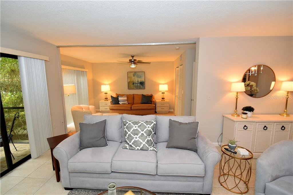 A living room features a light gray sofa, a tan sofa, and neutral decor — 1667 BROOKHOUSE CIRCLE UNIT BR128, SARASOTA, FL