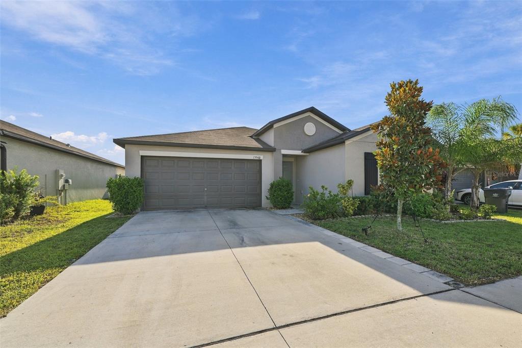 A single-story house with a two-car garage, concrete driveway, and a small front yard — 15540 PEACE RIVER PLACE, SUN CITY CENTER, FL