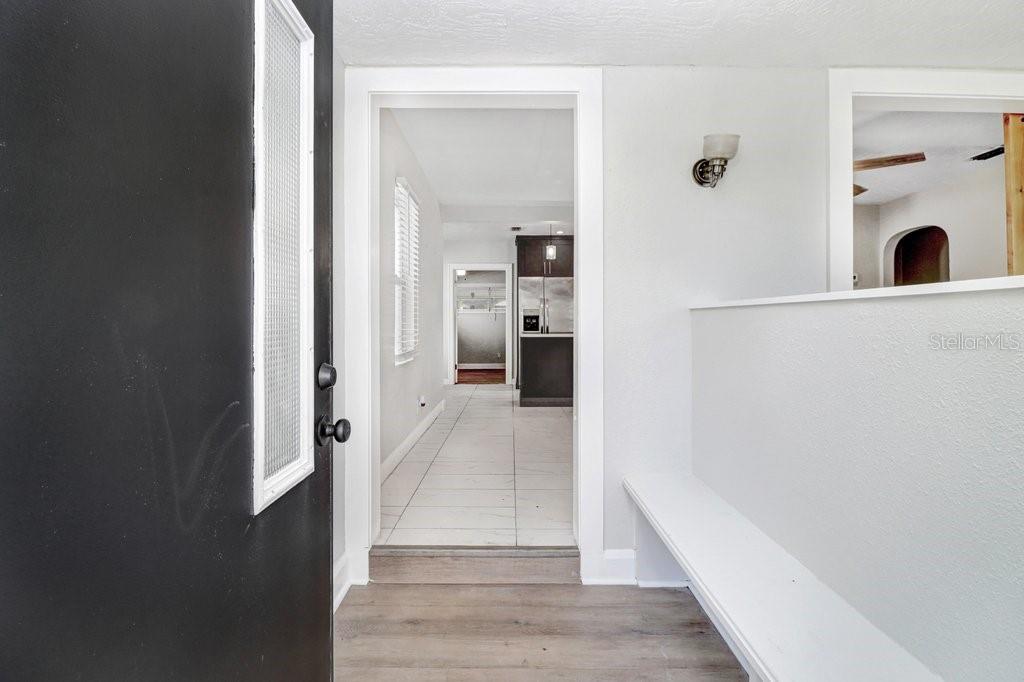 An entryway with a black door, white walls, wood-look flooring, and a built-in bench — 711 16TH AVENUE S, ST PETERSBURG, FL