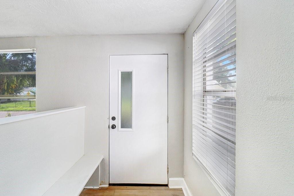 An interior entryway features a white door with a vertical glass panel and a built-in bench — 711 16TH AVENUE S, ST PETERSBURG, FL