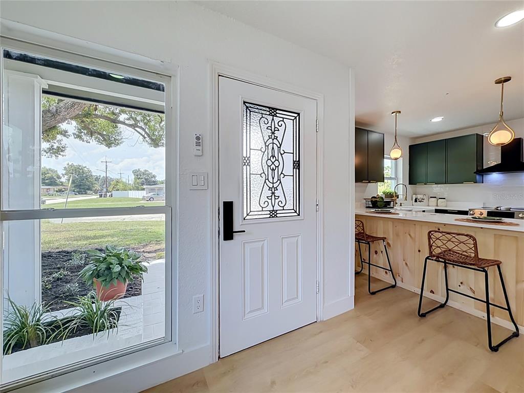 A white front door with a decorative glass insert opens into a kitchen with bar seating — 415 MERCADO AVENUE, ORLANDO, FL
