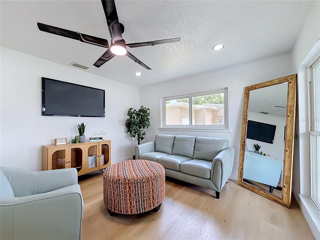 A living room features a light blue sofa, a patterned ottoman, and a large floor mirror — 415 MERCADO AVENUE, ORLANDO, FL
